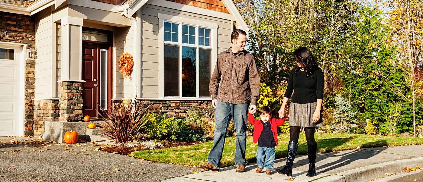 Family walking hand-in-hand along sidewalk