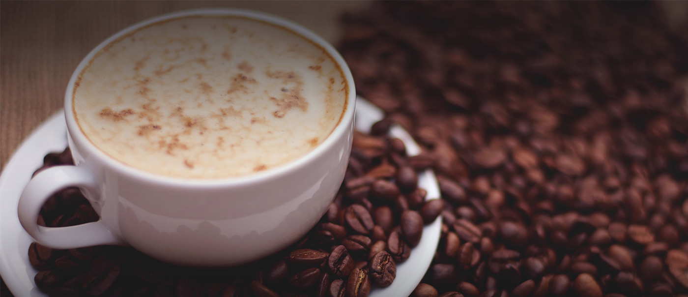 Cup of coffee surrounded by coffee beans