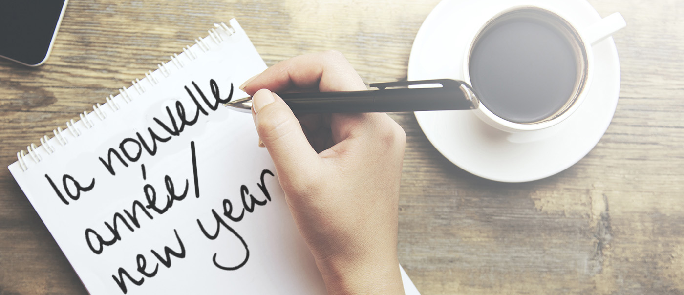 Hand writing on a piece of paper next to a cup of coffee