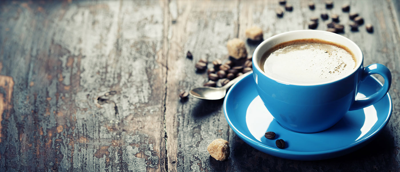 Blue coffee cup filled with coffee on wood tabletop