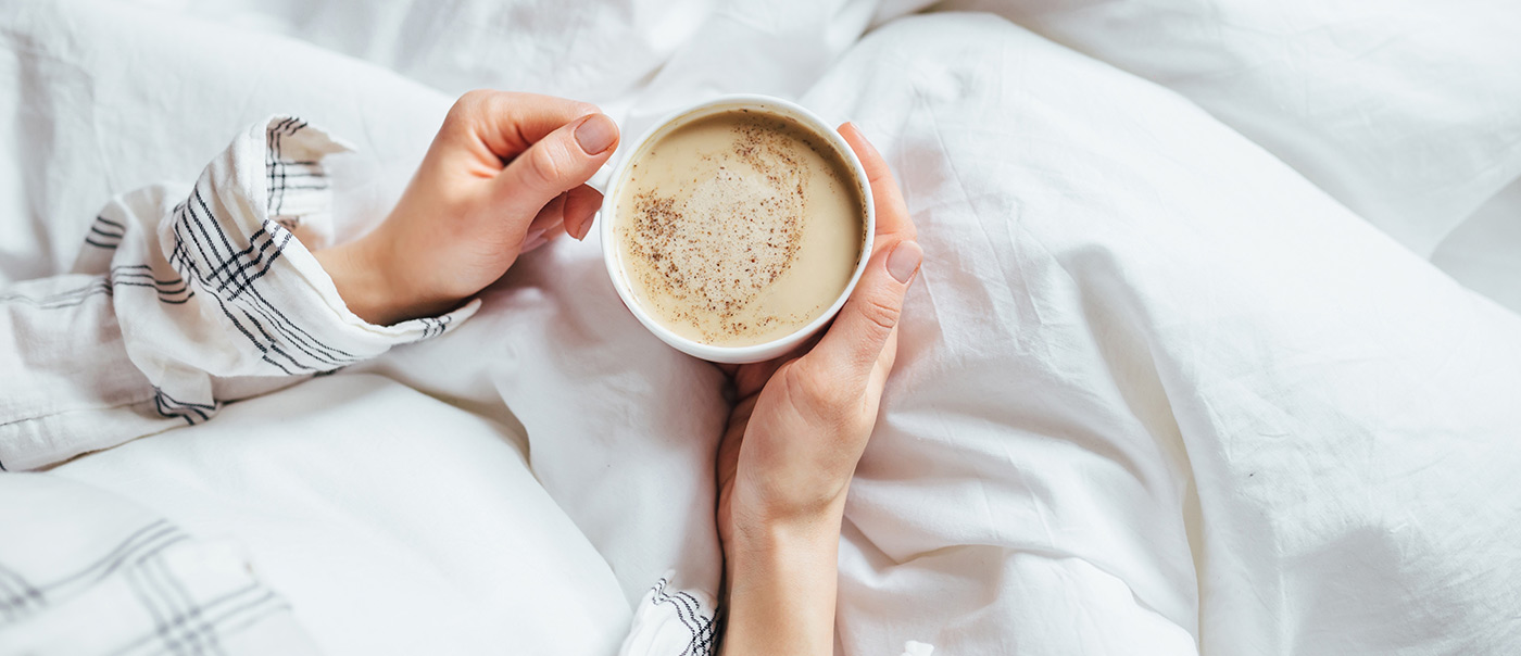 A person drinking coffee in bed