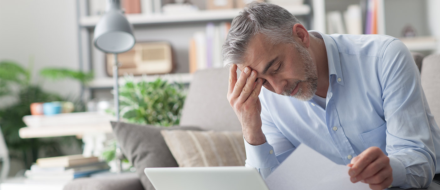 Man looking at computer and paper work