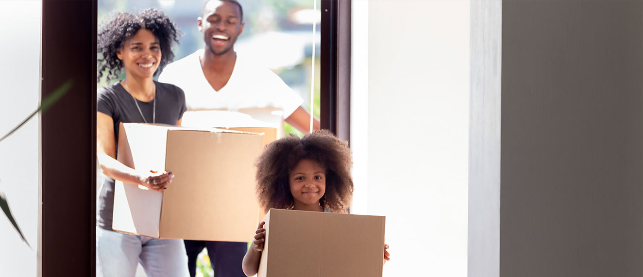 Family moving into new house carrying boxes