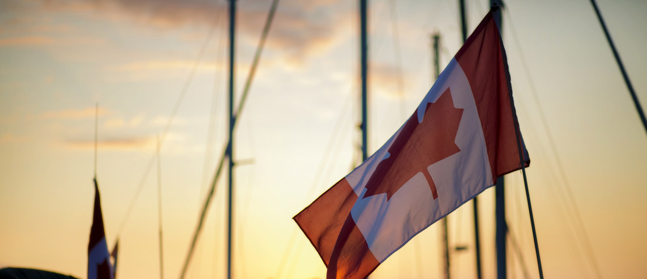 A Canadian flag waves in front of a sunset