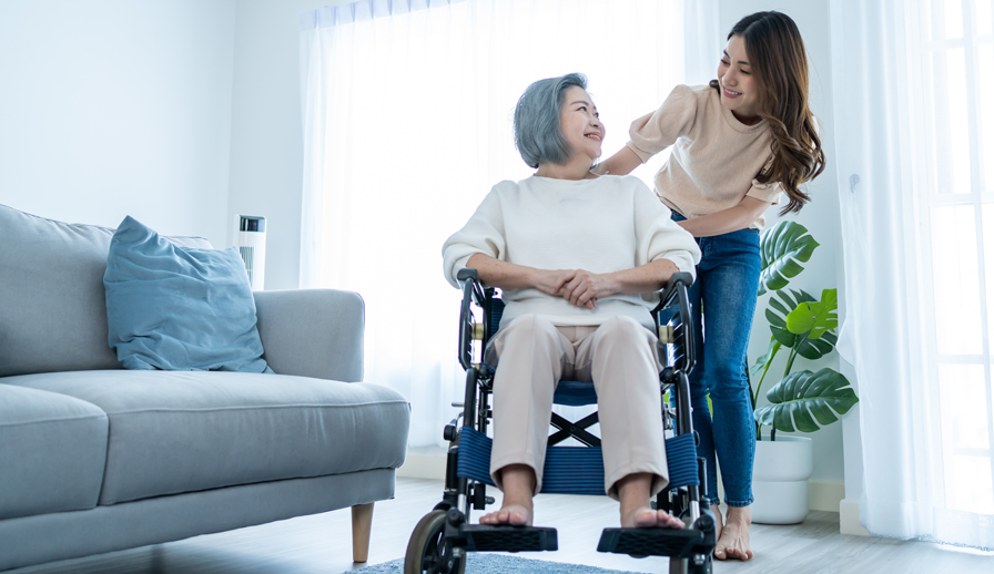 Parent sitting in wheelchair, daughter leaning over