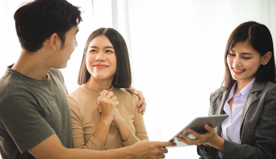 Young couple talking to REALTOR(r) holding paperwork