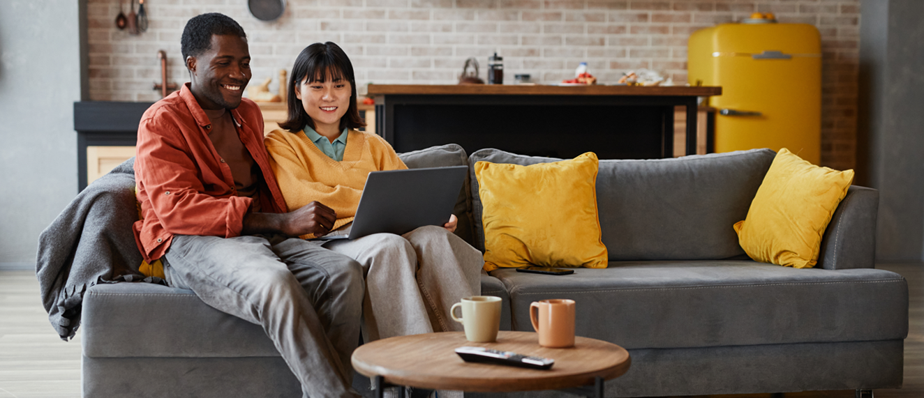 Young couple sits on a couch in their new home.