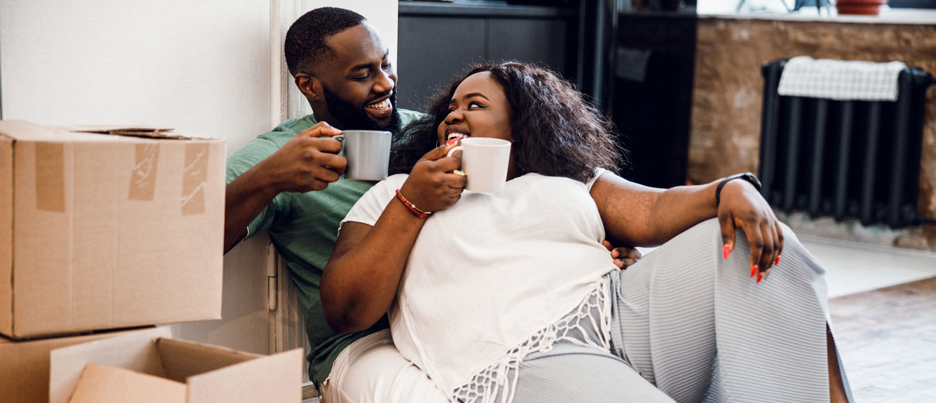 Couple sitting around moving boxes drinking coffee