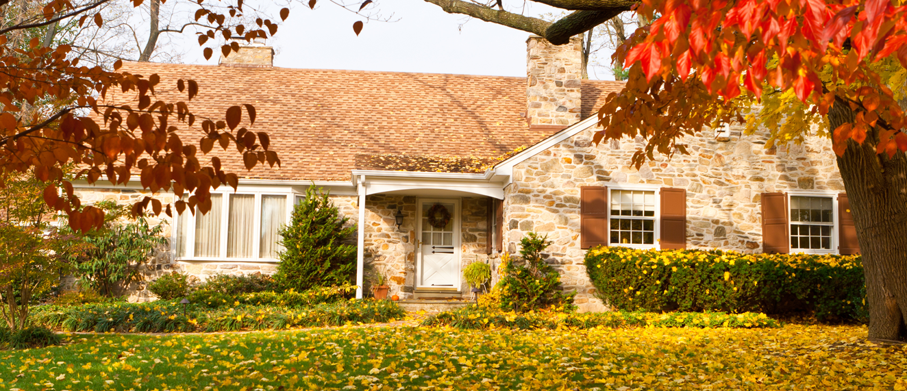 Brick house surrounded by fall leaves.