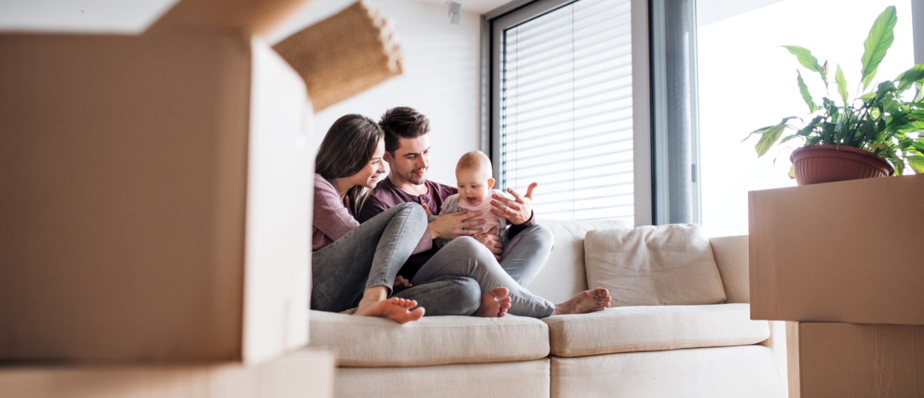 Family sitting on couch surrounded by moving boxes.