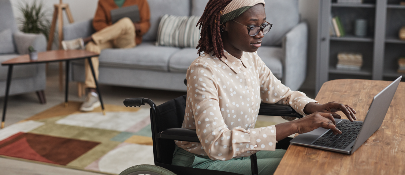 Woman in a wheelchair sits at a desk in an accessible home.