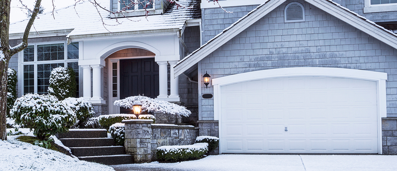 Snow on Driveway leading to home with a garage.