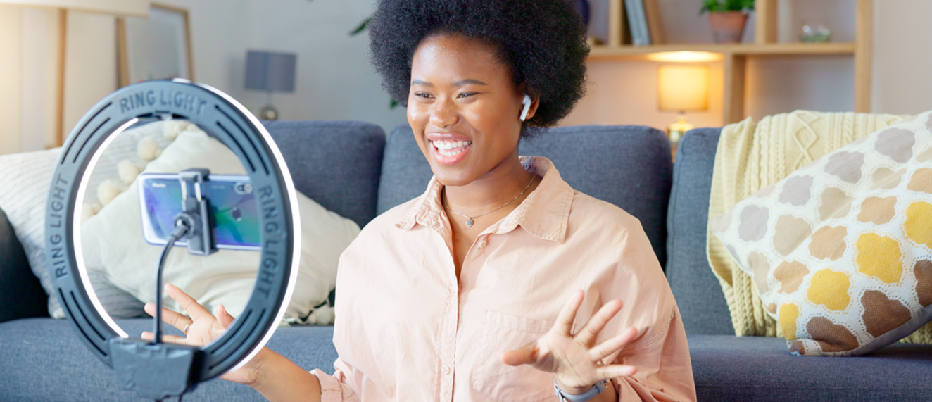 Woman speaking to camera on ring light, working on her online presence.