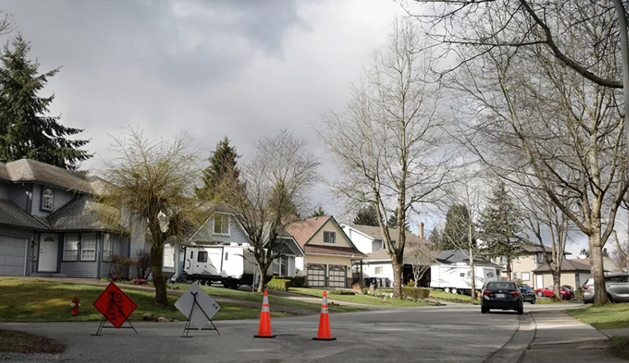 Suburban street with construction signs blocking way. 