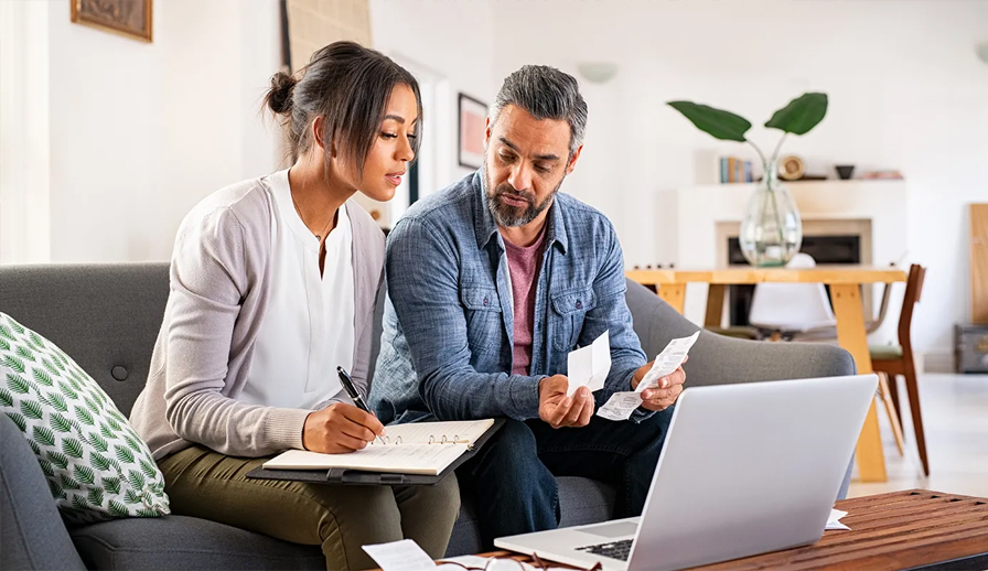 Couple sitting on couch looking at laptop. 