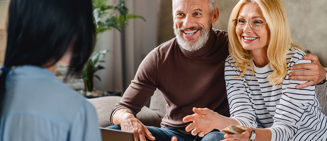 Couple happy sitting on couch talking to a real estate agent.