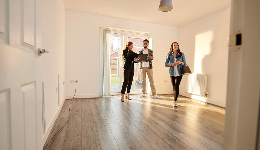 Couple looking at empty home with a real estate agent.