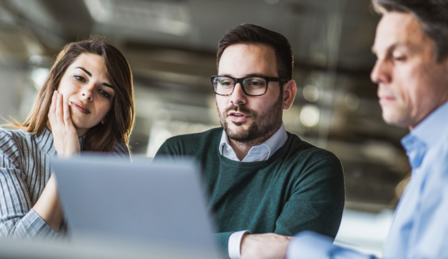 Couple looking at computer screen with man.