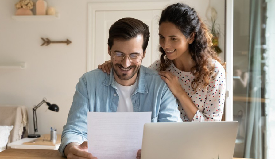 Couple smiling and looking at piece of paper. 