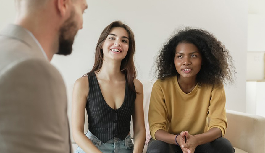 Female couple speaking with man.