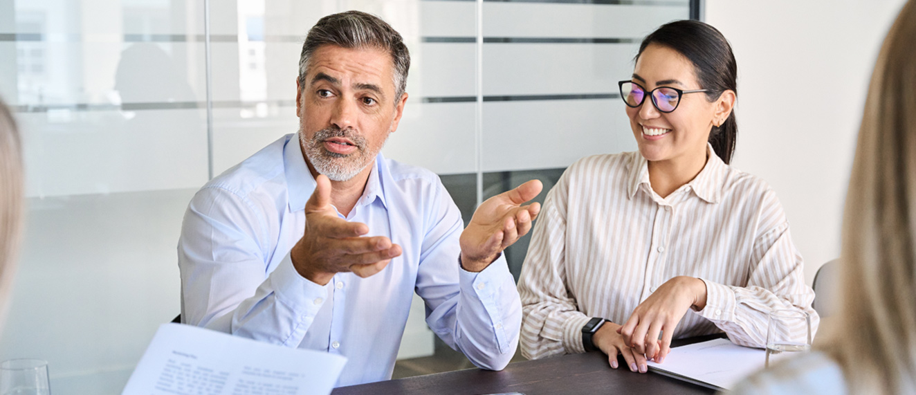 Man and woman sitting at conference table talking.