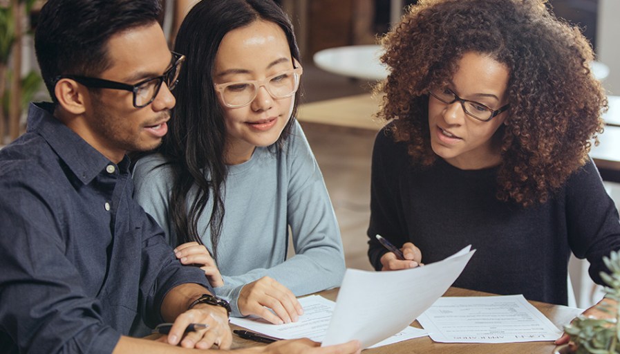 Three people looking over documents. 